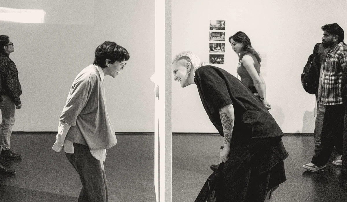 Visitors stopping in front of works in a gallery.