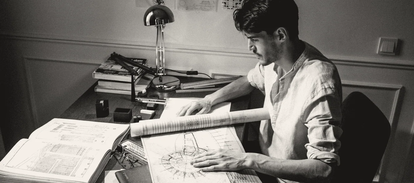 A drawing desk with plans, a scale rule and a pencil.