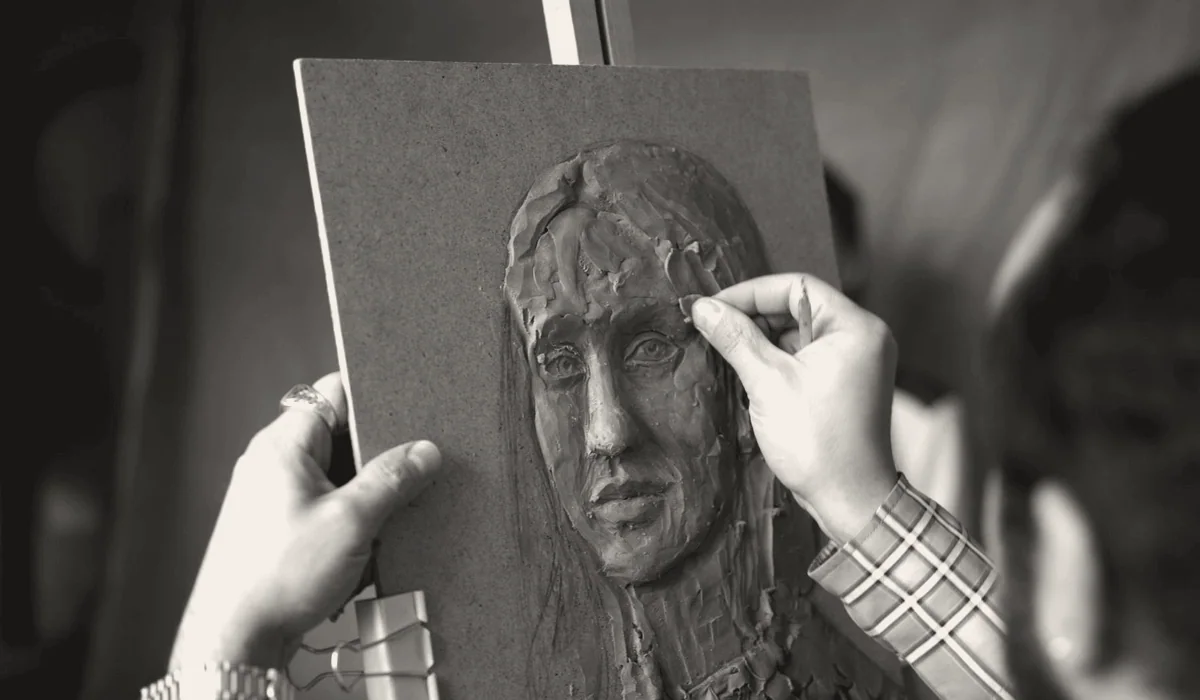 A sculptor shaping a clay model in a studio.